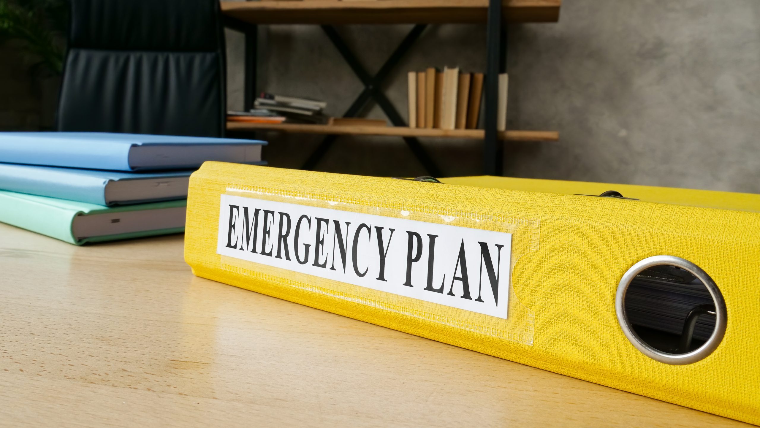 Yellow folder labelled "emergency" on a desk.