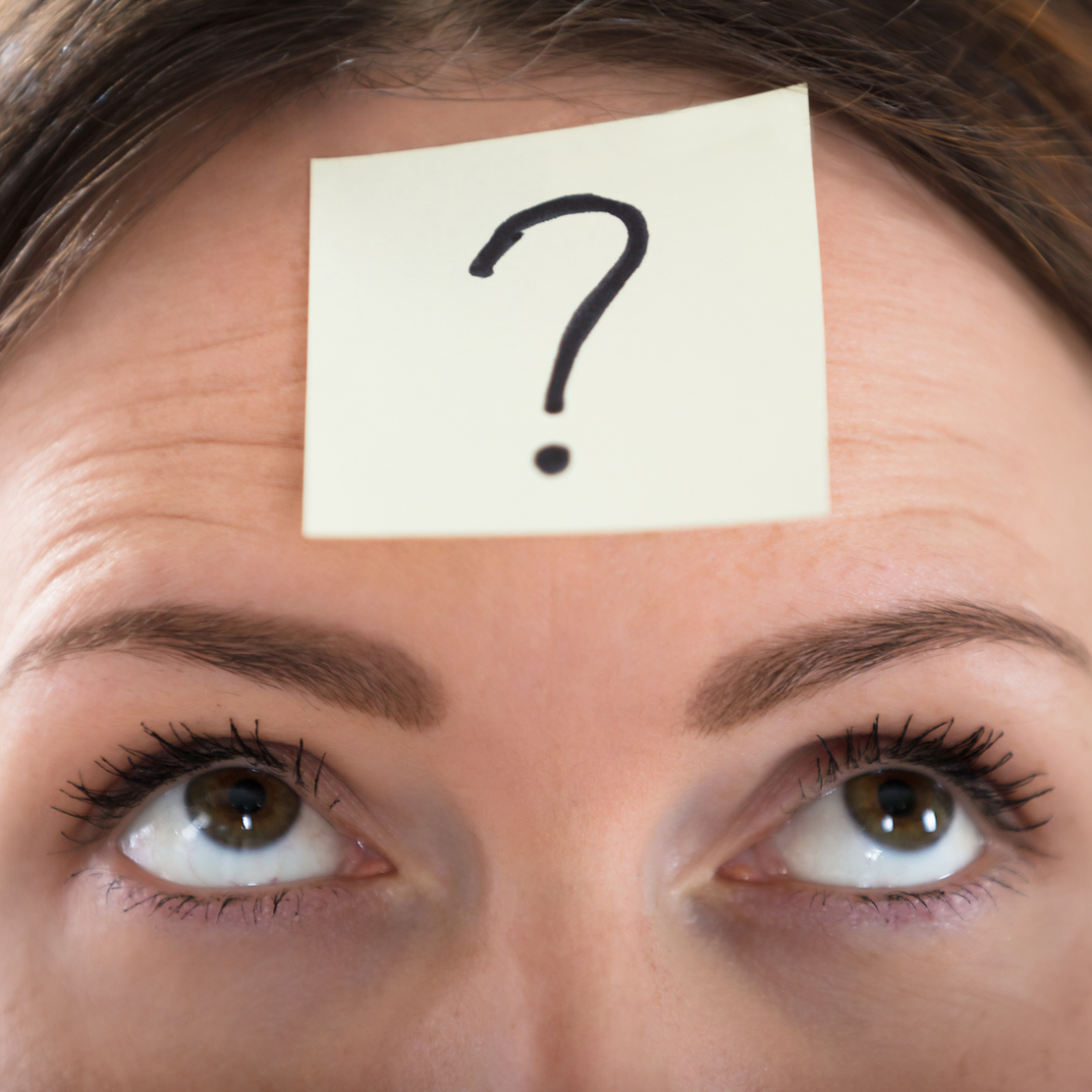 a sticky note with a question mark on top of a person's forehead