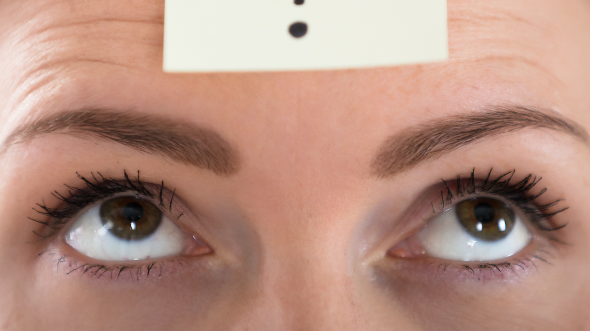 a sticky note with a question mark on top of a person's forehead