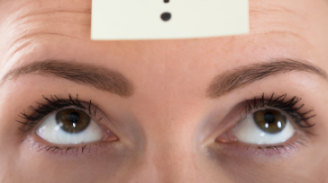 a sticky note with a question mark on top of a person's forehead