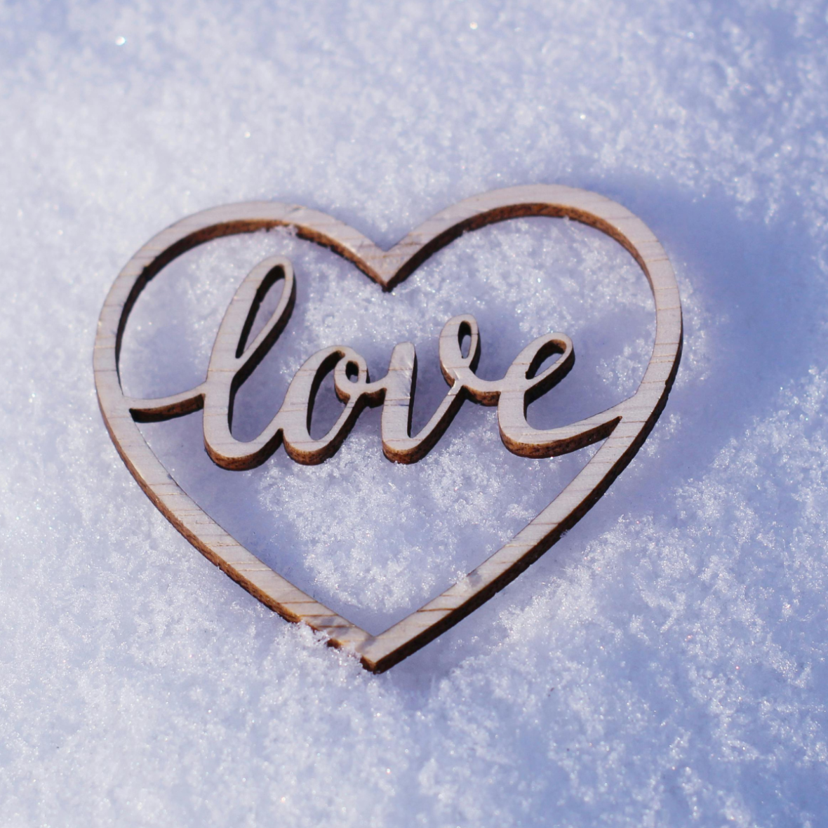 a cutout heart laying in snow with text reading "love"