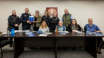 Group photo of University of Maine at Augusta representatives presenting the 100% Award for Community Policing Education to the Monmouth Police Department at a Monmouth Select Board meeting.