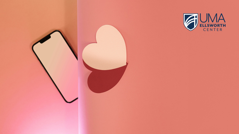 A smartphone lies on a pink gradient background, partially separated by a vertical shadow from a white heart shape on the right,