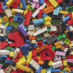 A large pile of colorful plastic building bricks in various shapes and sizes, scattered and overlapping in a close-up view.