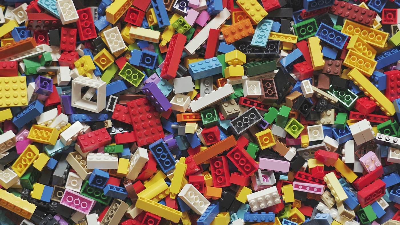 A large pile of colorful plastic building bricks in various shapes and sizes, scattered and overlapping in a close-up view.