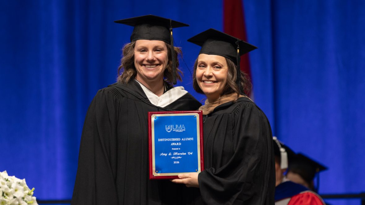 Amy Marston holding her Distinguished Alumni Award plaque presented by Kristen Eaton