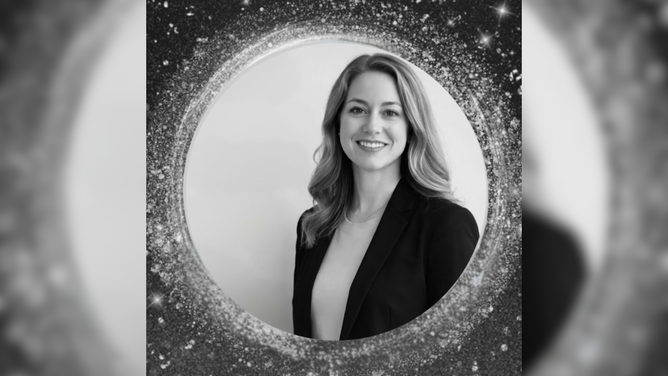 A smiling woman with long hair and wearing a blazer is framed within a circle of star-like points of light.