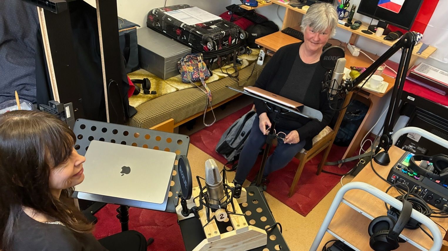 Dr. Magda Nisponska and Dr. Sharon McMahon Sawyer record an episode of the Mentalizing Mediation podcast series in a small studio, seated near microphones, laptops, headphones, and audio equipment.