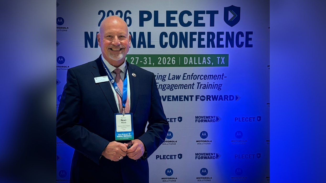 Noel March smiles while standing in front of a 2026 PLECET National Conference display.