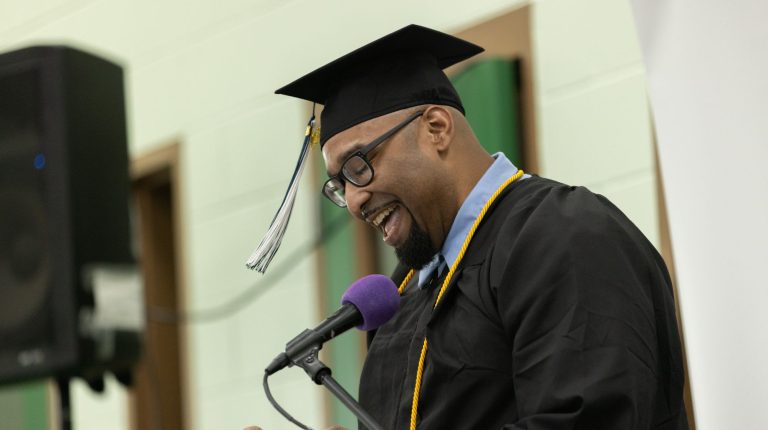 A man in graduation cap and gown addresses the audience at the 2026 UMA PEP commencement ceremony