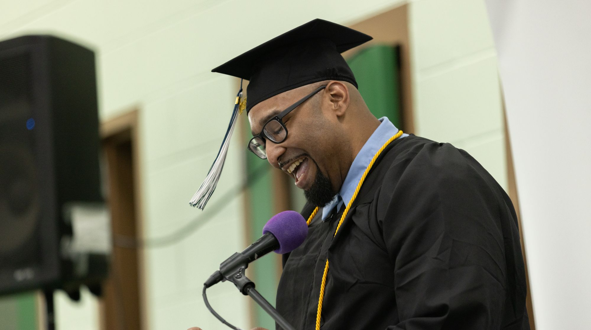 A man in graduation cap and gown addresses the audience at the 2026 UMA PEP commencement ceremony