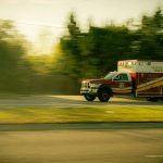 an ambulance in motion along a road in a wooded area