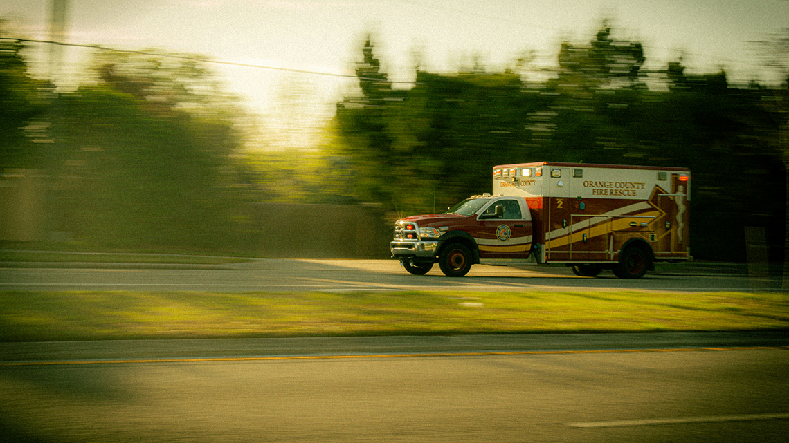 an ambulance in motion along a road in a wooded area
