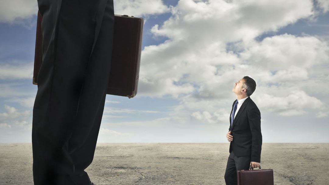 an average sized man with a briefcase looks up at a giant with a briefcase
