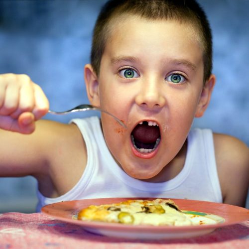 a messy child eating pizza with a fork