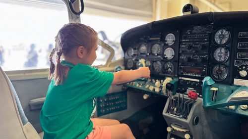 potential aviation student sitting at plane controls during kids in aviation day in brunswick's hangar 6