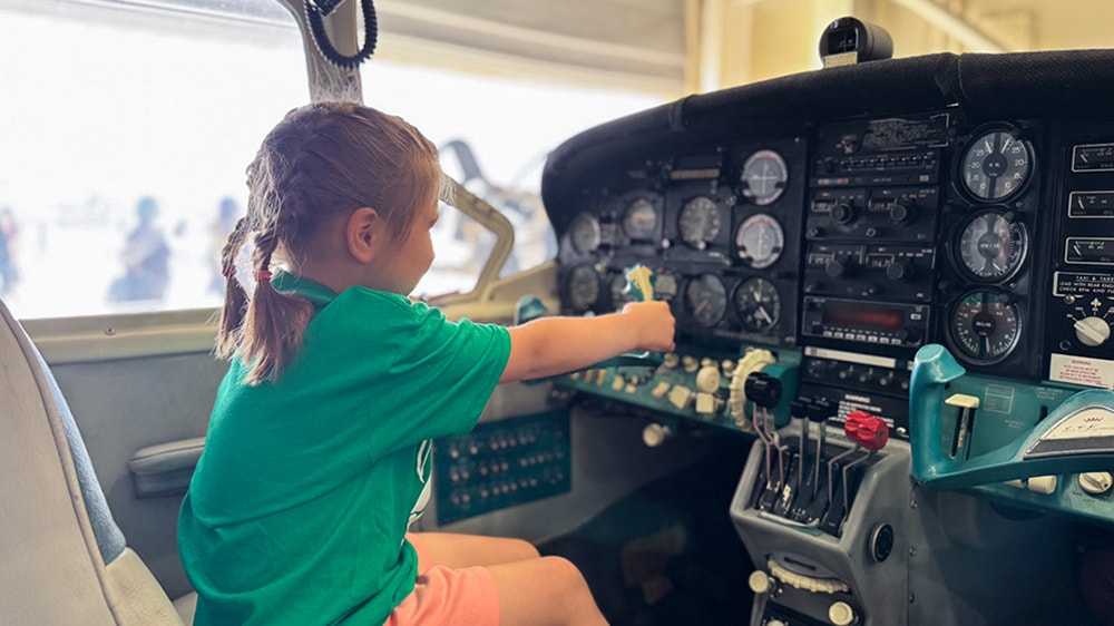 potential aviation student sitting at plane controls during kids in aviation day in brunswick's hangar 6
